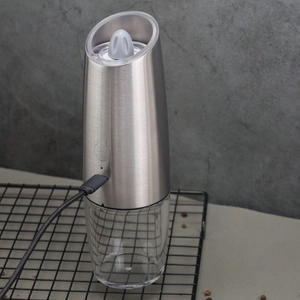 Electric stainless steel pepper grinder with USB charging cable on a modern kitchen counter