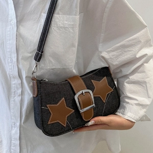 Detail of blue denim underarm bag with brown leather star patches and buckle closure