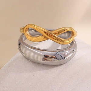 Dettaglio macro dell'anello infinito dorato e della fascia larga in argento lucido