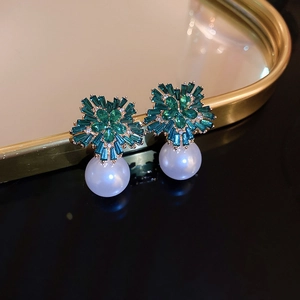 Close-up of vintage flower-shaped pearl earrings with green crystals and gold plating
