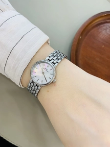 Detailed shot of women's silver watch with white mother-of-pearl dial and metallic band