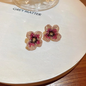 Close-up of handmade floral earrings with red and purple beads and rose gold wire