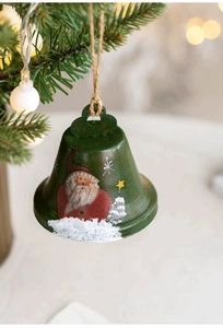 Detailed view of green Christmas bell with Santa and star motifs hanging on a tree