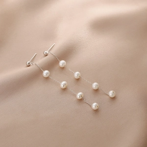 Detailed macro shot of long silver tassel earrings featuring natural freshwater pearls