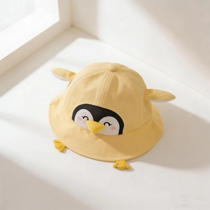 Macro detail view of yellow toddler bucket hat featuring cute cartoon penguin design