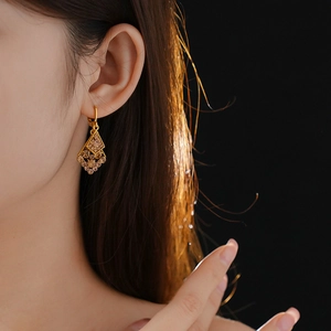 Close-up of a leaf-shaped gold earring with champagne diamonds on a model's ear