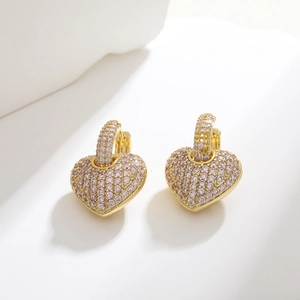 Macro shot of gold heart-shaped earrings featuring pink-purple pavé-set cubic zirconia