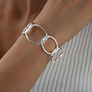 Close-up of a chunky silver chain bracelet with oversized oval links on a female wrist