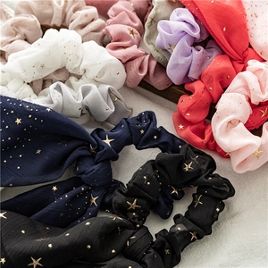 Flat lay of colorful chiffon scrunchies with gold star patterns and long bow ribbons