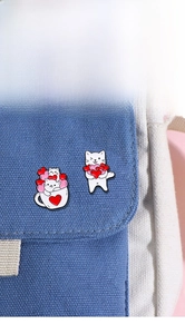 Close-up of cute cartoon cat pins with hearts attached to a blue canvas bag accessory