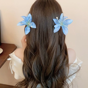 Detail view of a pair of light blue fabric hibiscus flower hair clips worn by a model