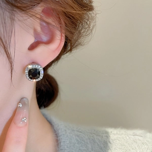 Detail of square black gemstone earrings with sparkling crystal halo on model