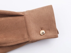 Close-up of brown suede dress sleeve featuring a decorative gold metallic button detail