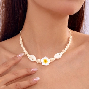 Close-up of bohemian summer necklace with white plumeria flower and seashell charms