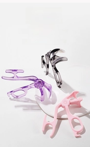 Close-up of three colorful resin eyelash applicators with built-in comb on white podiums
