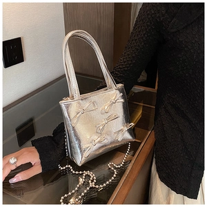 Silver metallic handbag featuring 3D bows and a classic pearl chain strap detail