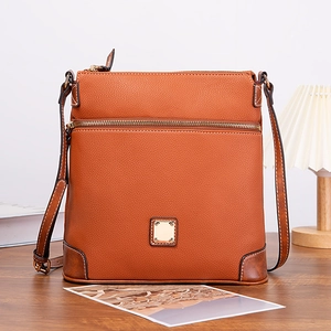 Detailed view of caramel pebble leather crossbody bag with golden square metal hardware