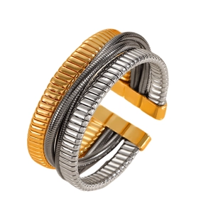 Detail of multi-layer metallic coil bracelet featuring gold, silver, and grey spring texture