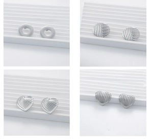 Detailed views of four silver stud earrings with circular and heart-shaped textured designs