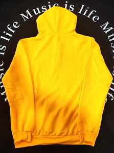 Détail d'un sweat à capuche jaune avec texture gaufrée et poignets côtelés