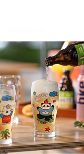 Detail showing beverage pouring into a glass with cute cartoon panda and cat illustrations