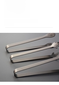 Macro detail of stainless steel tongs showing hanging U-shaped handles and brushed texture