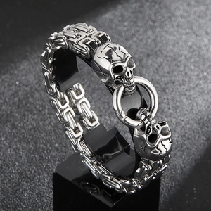 Macro detail of men's vintage silver punk double skull bracelet with woven chain links