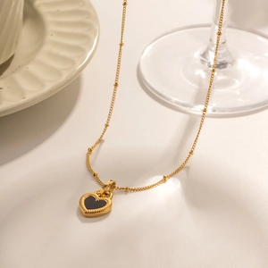 Detail of a vintage 18K gold heart necklace with black inlay on a white plate background