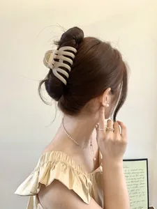 Detailed side view of a large cream pumpkin-shaped hair claw clip on a model's updo