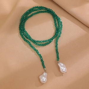 Detail of multi-layer necklace with green faceted beads and white baroque pearls on silk