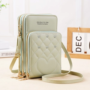 Detailed view of mint green crossbody bag featuring three zip pockets and heart quilting