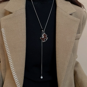 Brown horse pendant necklace with white pearl detail on model with brown suit