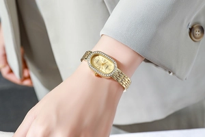 Gros plan d'une montre à quartz dorée ovale avec strass portée au poignet d'un mannequin