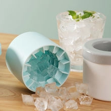 Macro detail of a light blue silicone ice cube maker and white bucket on a wooden surface