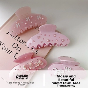 Detail of pink acetate hair claws with delicate white bows, pearls and sparkling rhinestones