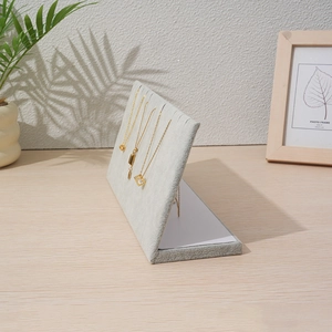 Gray velvet vertical necklace display stand with multiple slots on a wooden desk