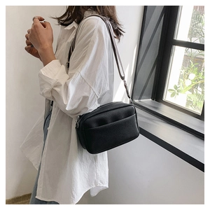 Fashionable black pebble leather crossbody bag with wide adjustable strap worn by model