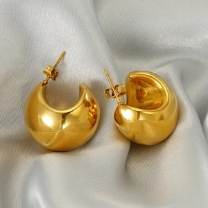 Polished gold crescent moon earrings displayed on elegant grey silk fabric backdrop