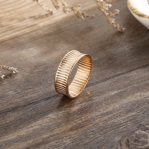 Detailed macro view of an 18K gold-plated wide band ring with vertical striped texture