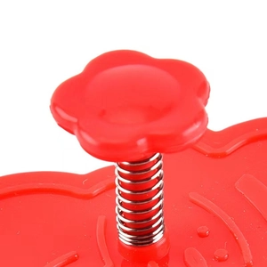 Close-up of red plastic cookie mold plunger with metal spring for DIY baking tools