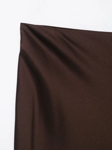 Close-up of elegant dark brown satin skirt fabric with smooth glossy silk-like texture