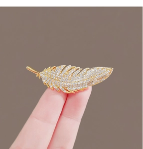Exquisite gold feather rhinestone brooch pin, detailed view of sparkling crystal jewelry accessory.