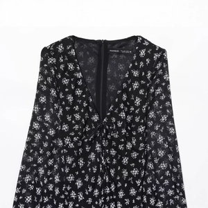 Chique zwarte jurk met V-hals en witte bloemenprint met gelaagde rok in boho-stijl