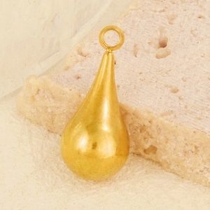 Macro shot of a polished golden teardrop pendant with a loop for DIY jewelry making