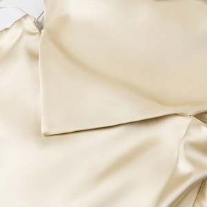 Macro detail of champagne gold satin fabric showing fine silk texture and elegant folds