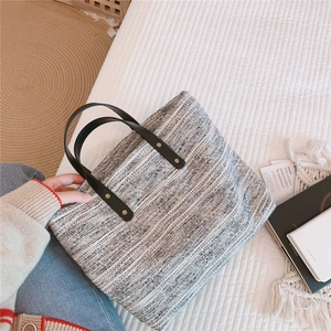 Détail du sac cabas en tweed avec poignée en cuir et rivets dorés sur fond de maison