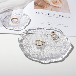 Irregular textured glass jewelry tray with gold earrings and ring on magazine background