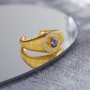 Macro shot of blue tanzanite gold plated ring with brushed finish and halo diamonds