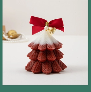 Detail of Christmas tree candle with red white gradient, bow, and golden bell decor