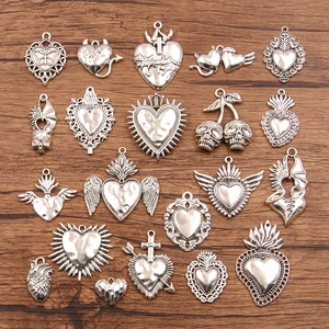 Halloween DIY silver heart and skull metal charms assortment on a rustic wooden background